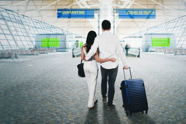 若いカップルのバックビューは 空港で隔離またはCovid 19テストの方向の間に立っている間に混乱して見えます — ストック写真