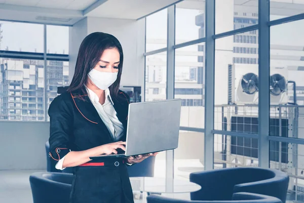 Kobieta Menedżer Pomocą Laptopa Stojąc Biurze Podczas Noszenia Maski Twarzy — Zdjęcie stockowe