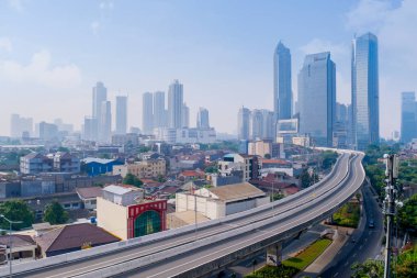 JAKARTA - Indonesia. June 29, 2021: Beautiful aerial view of misty Jakarta cityscape with quiet overpass road at morning time