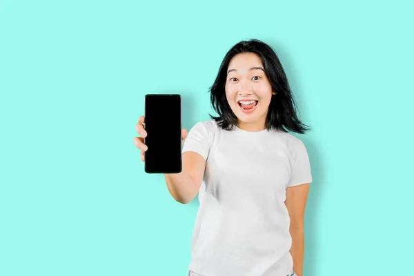 Счастливая Молодая Женщина Показывает Смартфон Пустым Экраном Стоя Смешным Лицом — стоковое фото