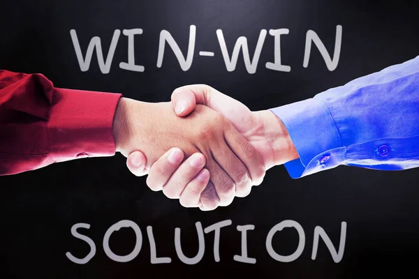 Close up of two businessmen shaking hands with win-win solution text in blackboard background