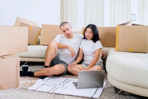 Young Couple Using Laptop Decorating New House Design While Sitting — Φωτογραφία Αρχείου