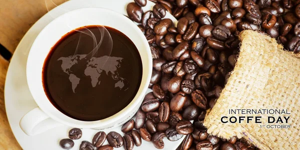 Top view of black coffee with world map on the cup on the table heap of coffee beans with International coffee day text