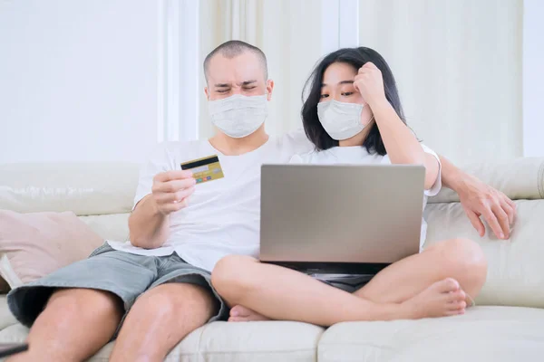 在网上购物的年轻夫妇 在家中自我隔离时 带着面具 使用笔记本电脑 — 图库照片
