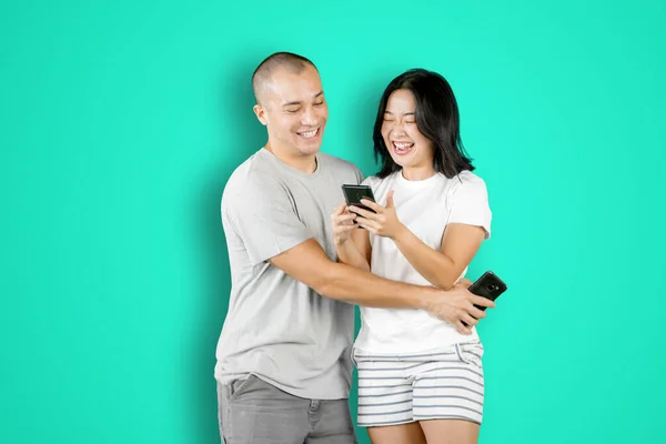 Joven Abrazando Esposa Mientras Usan Teléfono Móvil Juntos Estudio Con —  Fotos de Stock