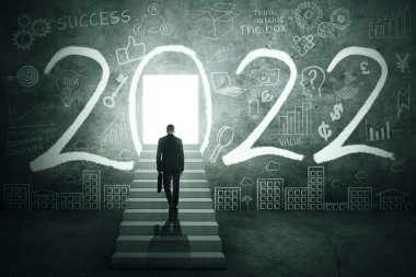 Erkek yöneticinin merdivenlerde bir bavul taşıdığı, 2022 numaralı ve tuğlaların üzerine karalamalar çizilen parlak bir kapıya doğru yürürken görüntüsü.