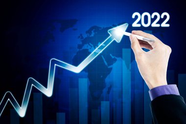 Dünya haritası arka planında 2022 rakamlı yukarı doğru ok çizmek için bir stil kalem kullanarak iş adamının elini kapat