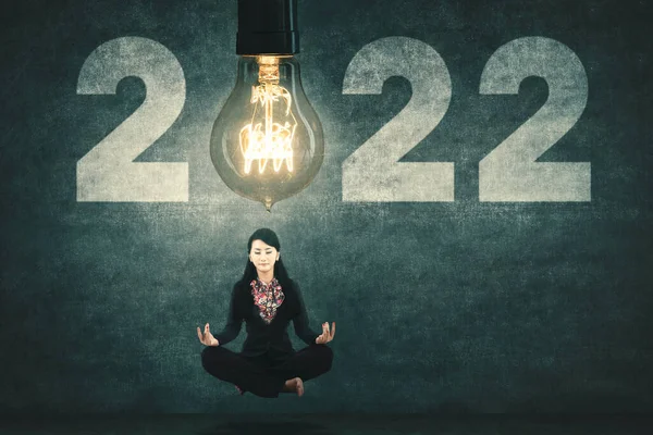 Eine Junge Geschäftsfrau Meditiert Während Sie Unter Einer Hellen Glühbirne — Stockfoto