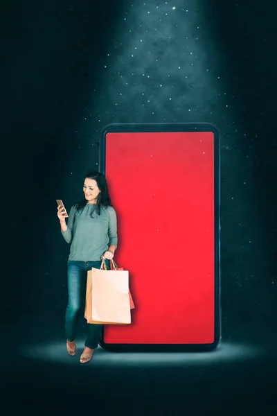 Молодая Женщина Держит Сумки Покупками Использует Мобильный Телефон Стоя Пустым — стоковое фото