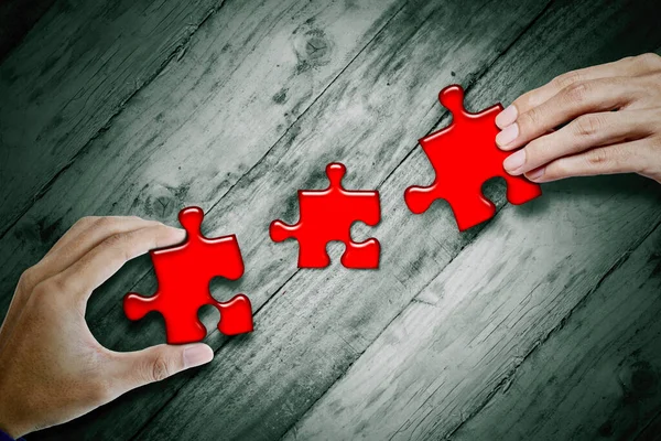 Close Rwo Hands Assembling Red Jigsaw Pieces Wooden Table While — Stock fotografie