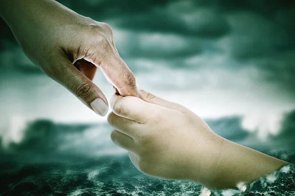 Father hands helps his son drowning on the overflowing river caused by rainstorm disaster