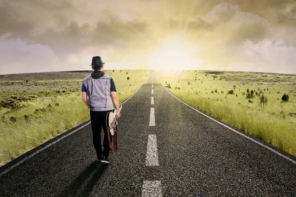 Lonely guitarist walking on road 1 — Stock Photo, Image