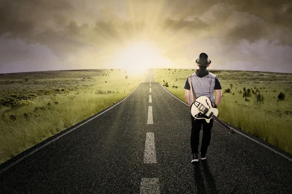 Samotny gitarzysta chodzenie na drodze — Zdjęcie stockowe