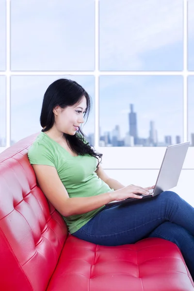 Mulher bonita trabalhando com laptop no sofá vermelho — Fotografia de Stock