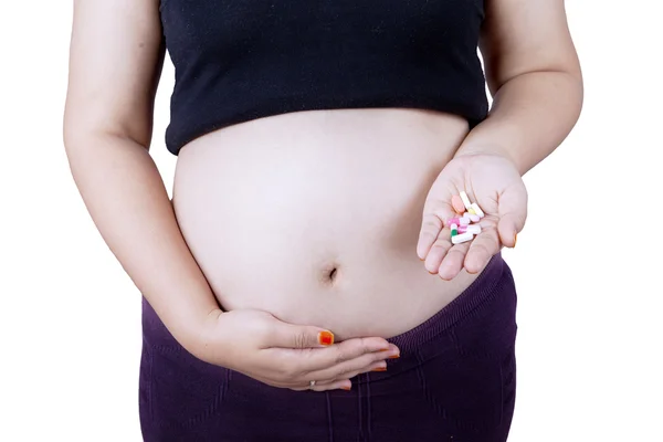 Pregnant tummy with pills on hand — Stok fotoğraf