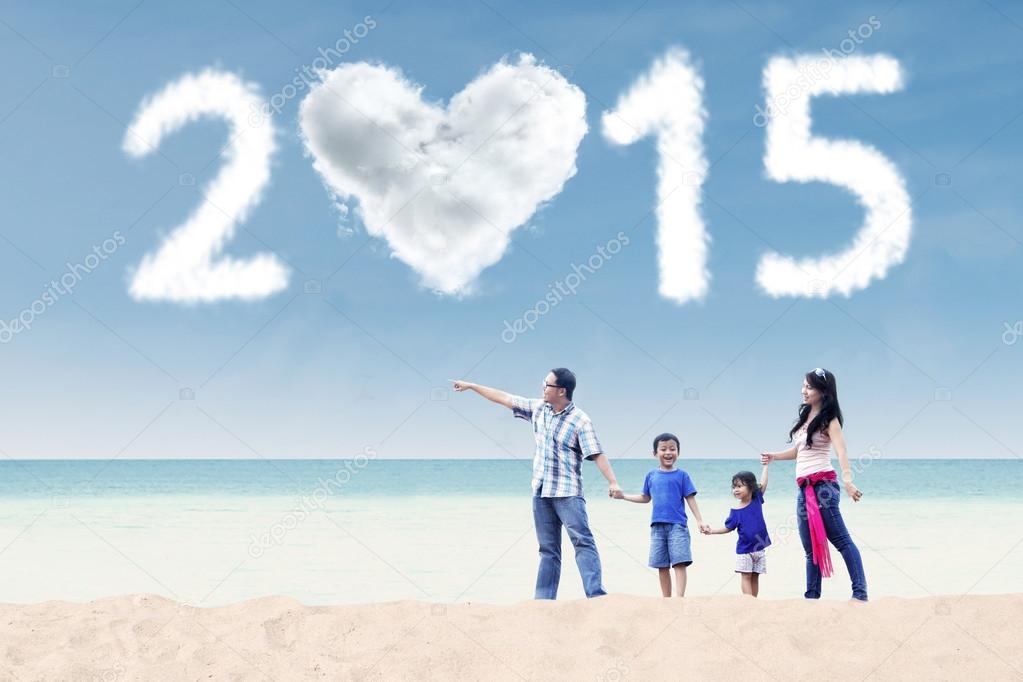 Family walking at beach under cloud of 2015