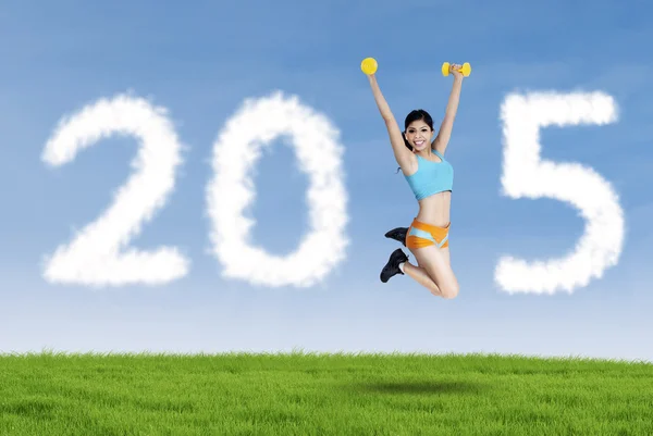 Asian woman with dumbbells in field — Stock Photo, Image