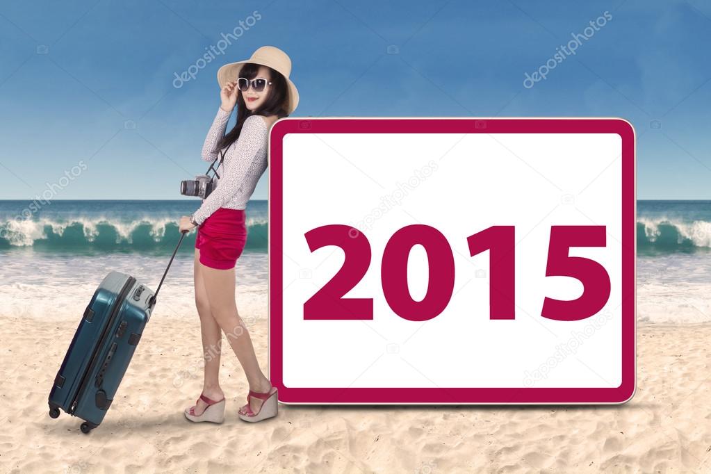 Hispanic woman with number 2015 on beach