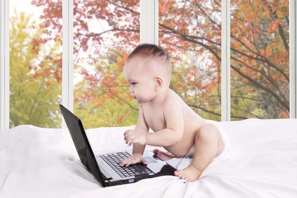 Baby girl with laptop on bedroom — Stock Photo, Image