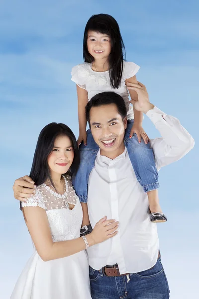 Familia sonriendo a la cámara bajo el cielo azul — Foto de Stock