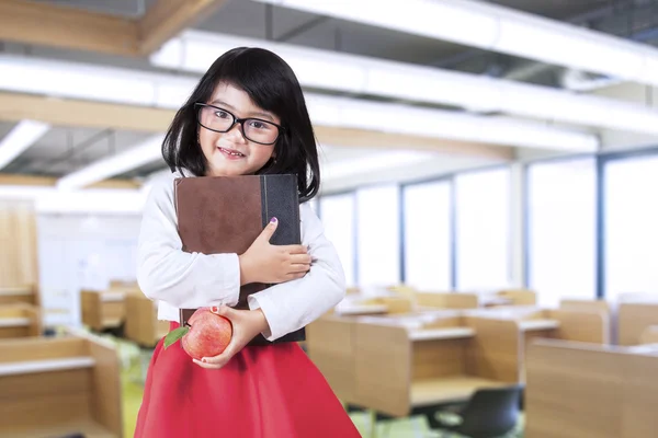 Kleines Mädchen hält ein Buch und einen Apfel — Stockfoto