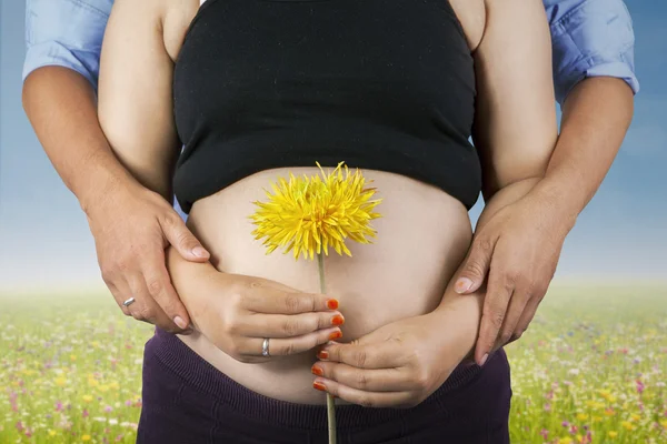 Pregnant woman and flower outdoors — Stock Photo, Image