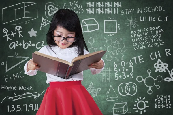 Söt liten flicka läser bok i klass — Stockfoto