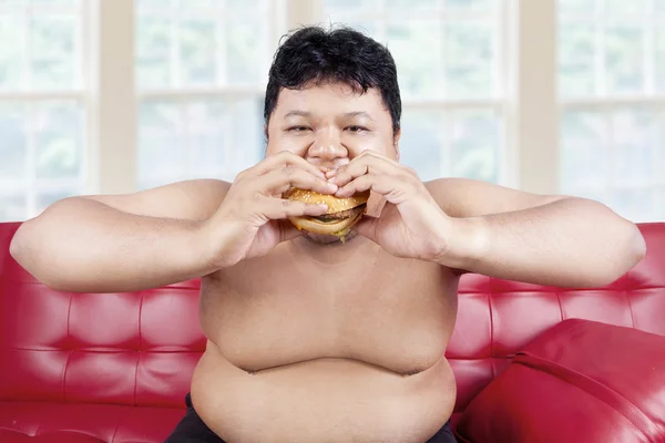Mann isst Hamburger zu Hause — Stockfoto