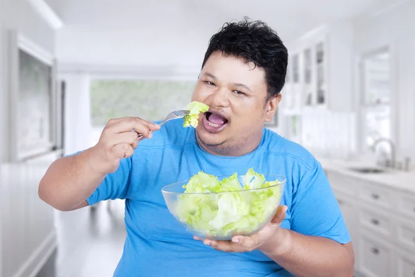 Hombre comiendo ensalada en la cocina — Foto de Stock