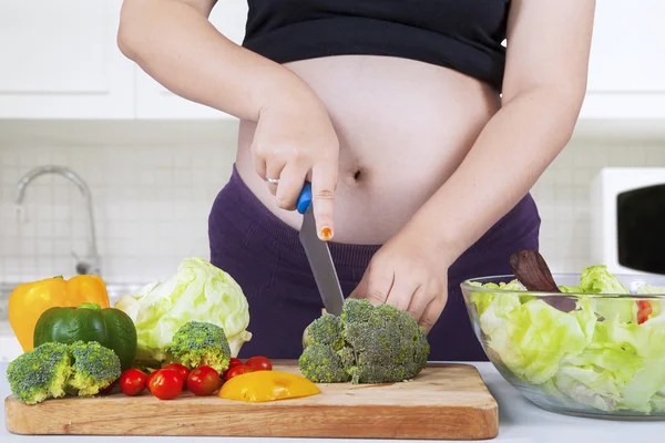 Gravida mamma skär broccoli — Stockfoto