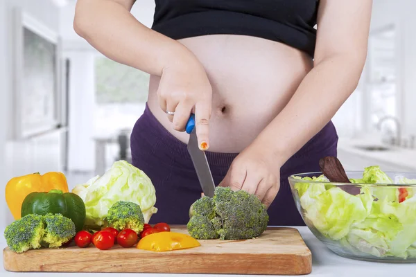 Mãe grávida prepara salada — Fotografia de Stock