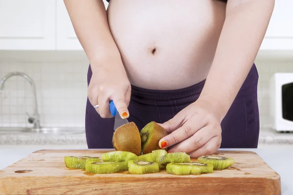 Donna incinta che taglia kiwi frutta — Foto Stock