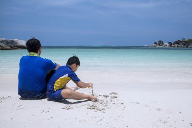 Baba ve oğul plaj üzerinde oturan