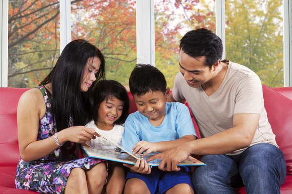 Los niños leen un libro de cuentos con sus padres — Foto de Stock