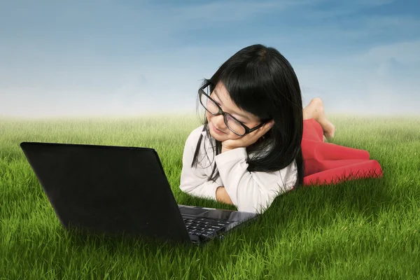 Menina bonito com laptop no prado — Fotografia de Stock