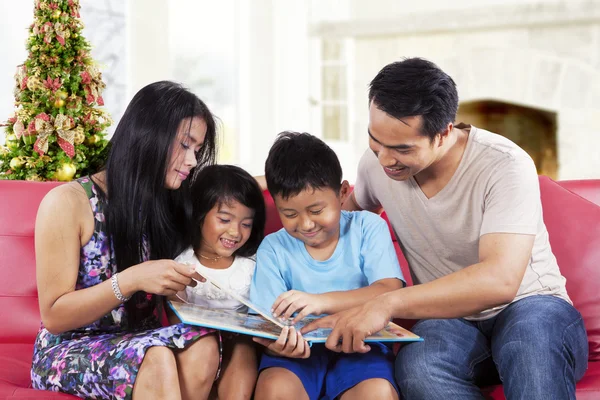 Glückliche Familie hält ein Geschichtsbuch in der Hand — Stockfoto