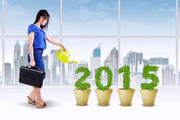 Woman watering the trees shaped number — Stock Photo, Image