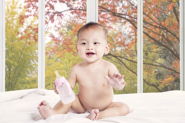 Baby spielt mit Milchflasche im Bett — Stockfoto