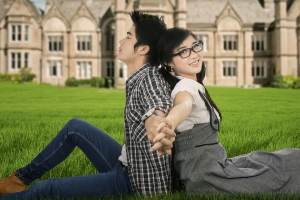 Pareja sentada en el parque universitario — Foto de Stock