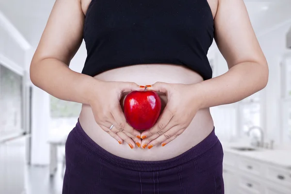 Pregnant tummy with red apple — Stock Photo, Image