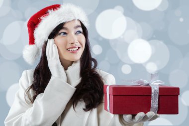 Noel Baba şapkalı bir hediye kutusu tutarak Asyalı kız