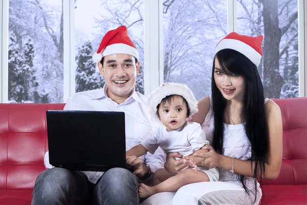 Linda chica en sombrero de santa usando portátil con la familia — Foto de Stock