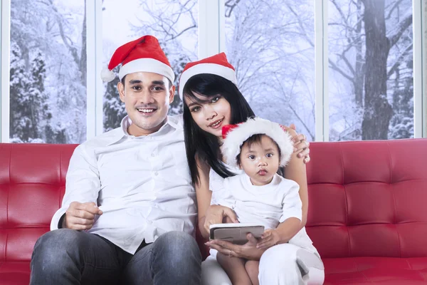 Rodziny z santa hat siedząc na kanapie — Zdjęcie stockowe