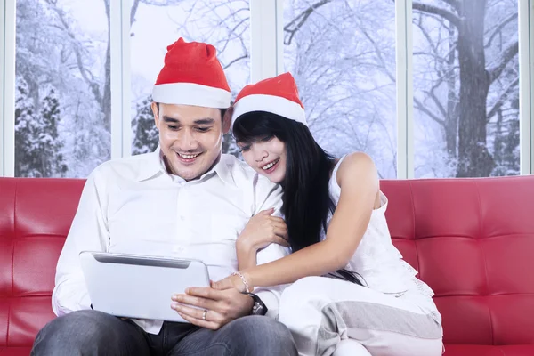 Hispanic couple in santa hat using tablet — Stock Photo, Image