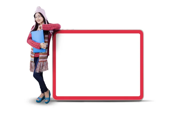 Školačka v teplé oblečení naklání na billboard — Stock fotografie