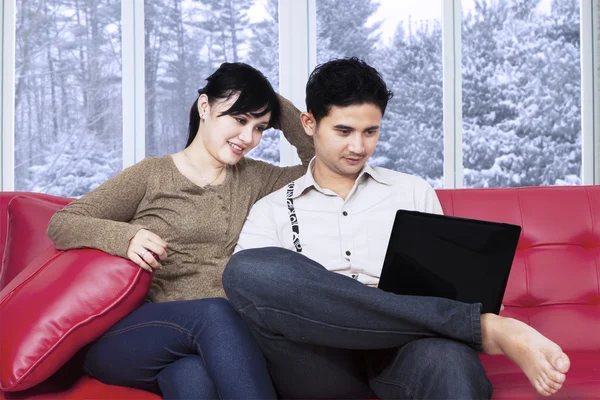 Paret sitter på soffan med bärbar dator — Stockfoto