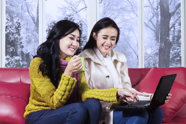 Happy girls in warm clothes using laptop — Stock Photo, Image