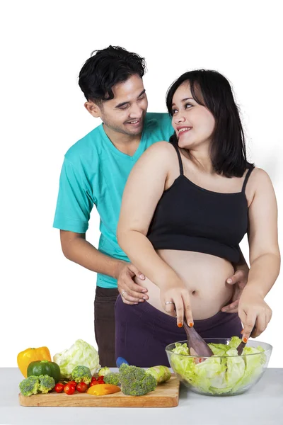 Pregnant mother and husband cooking salad — Stock Photo, Image