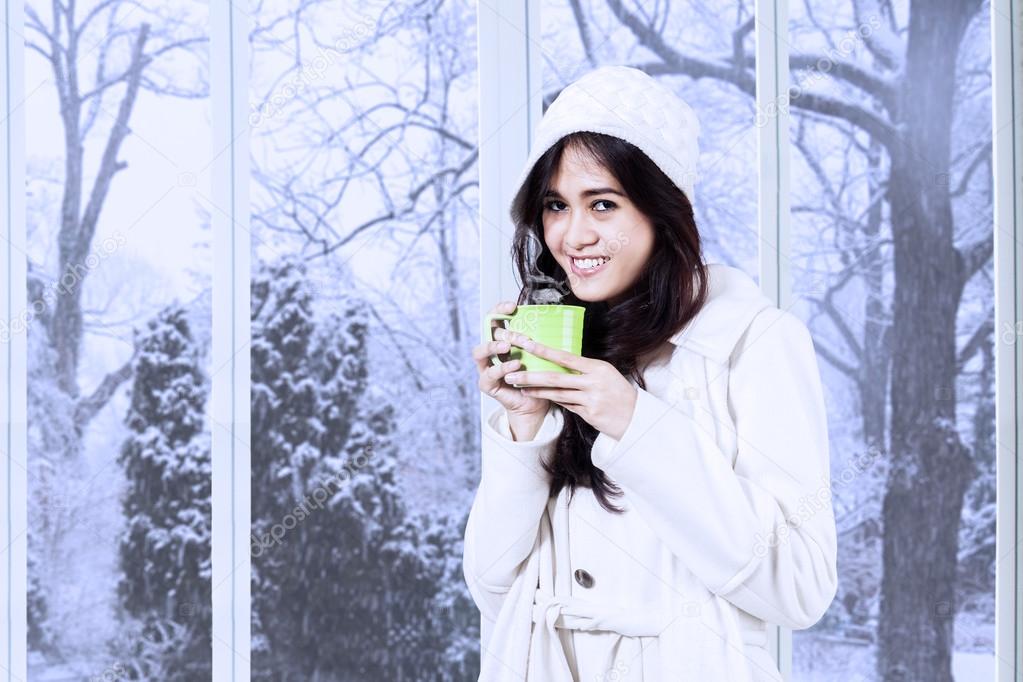 Lovely woman in winter coat drinks coffee
