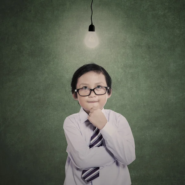Business boy thinking gesture under lit bulb — Stock Photo, Image